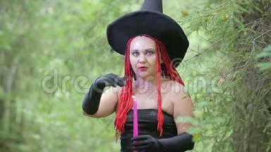 带着红色头发和尖尖帽子的迷人年轻女巫在森林里用蜡烛召唤